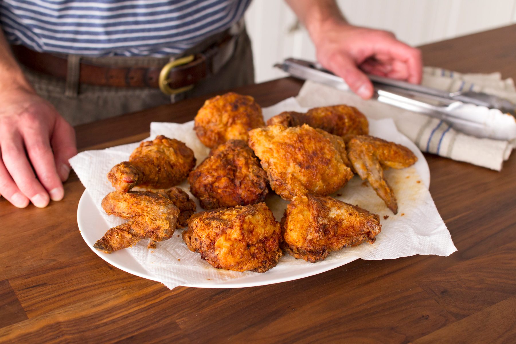 fresh fried chicken rests on a bed of paper towel on a white plate