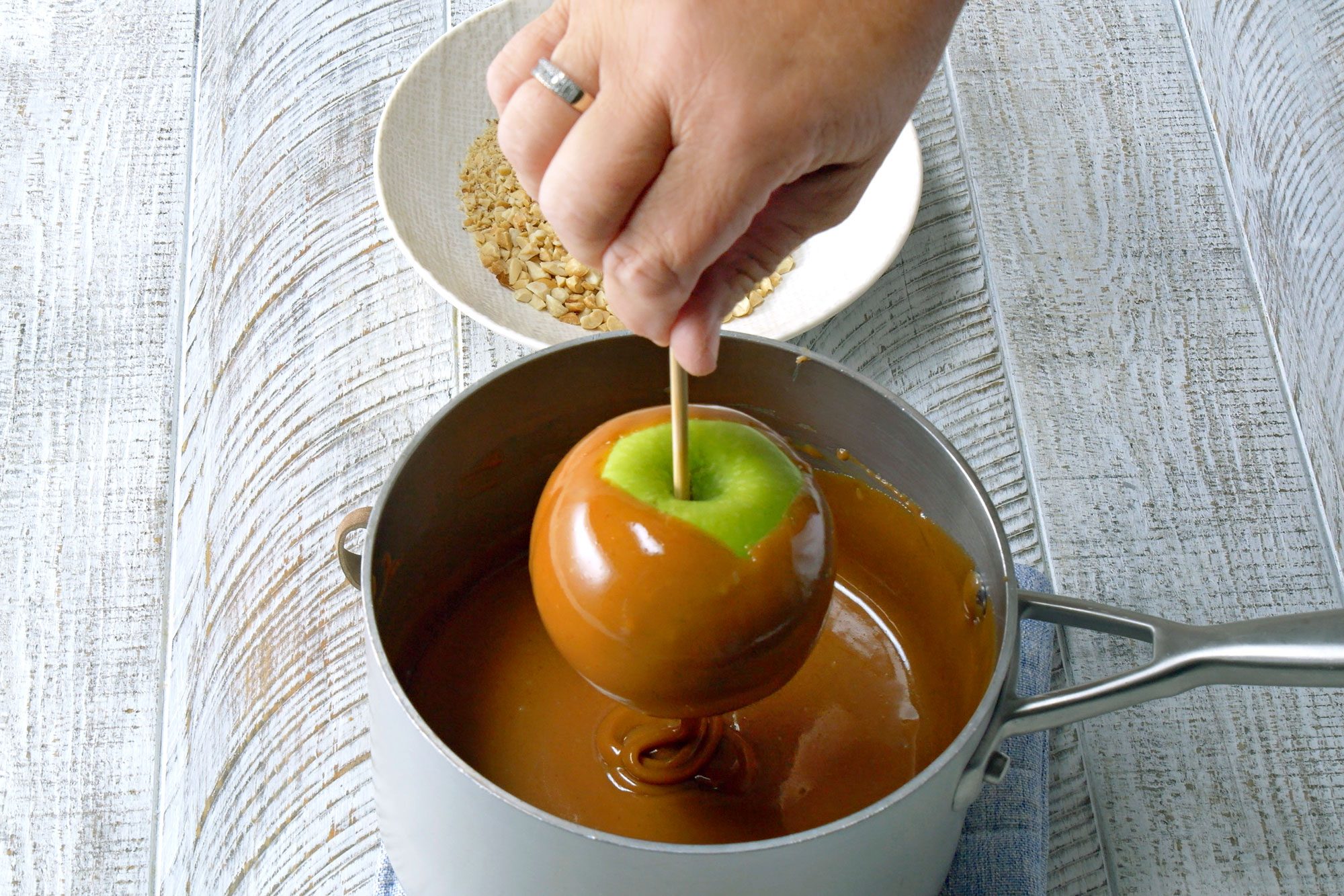 Insert wooden sticks into apples and Dip each apple into hot caramel mixture