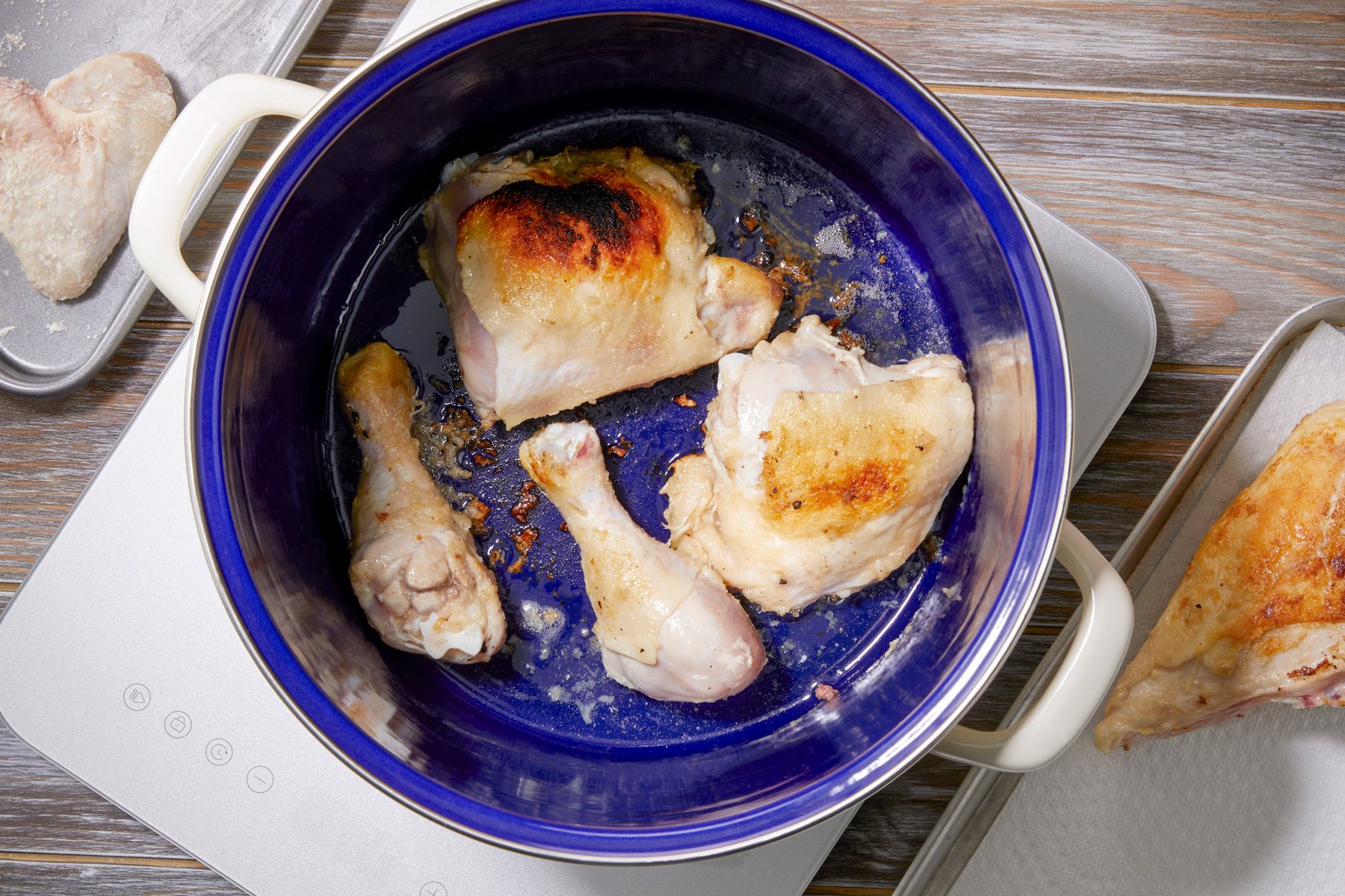 overhead shot; wooden background; Heating oil in stock pot and brown chicken on all sides then removing it from pan