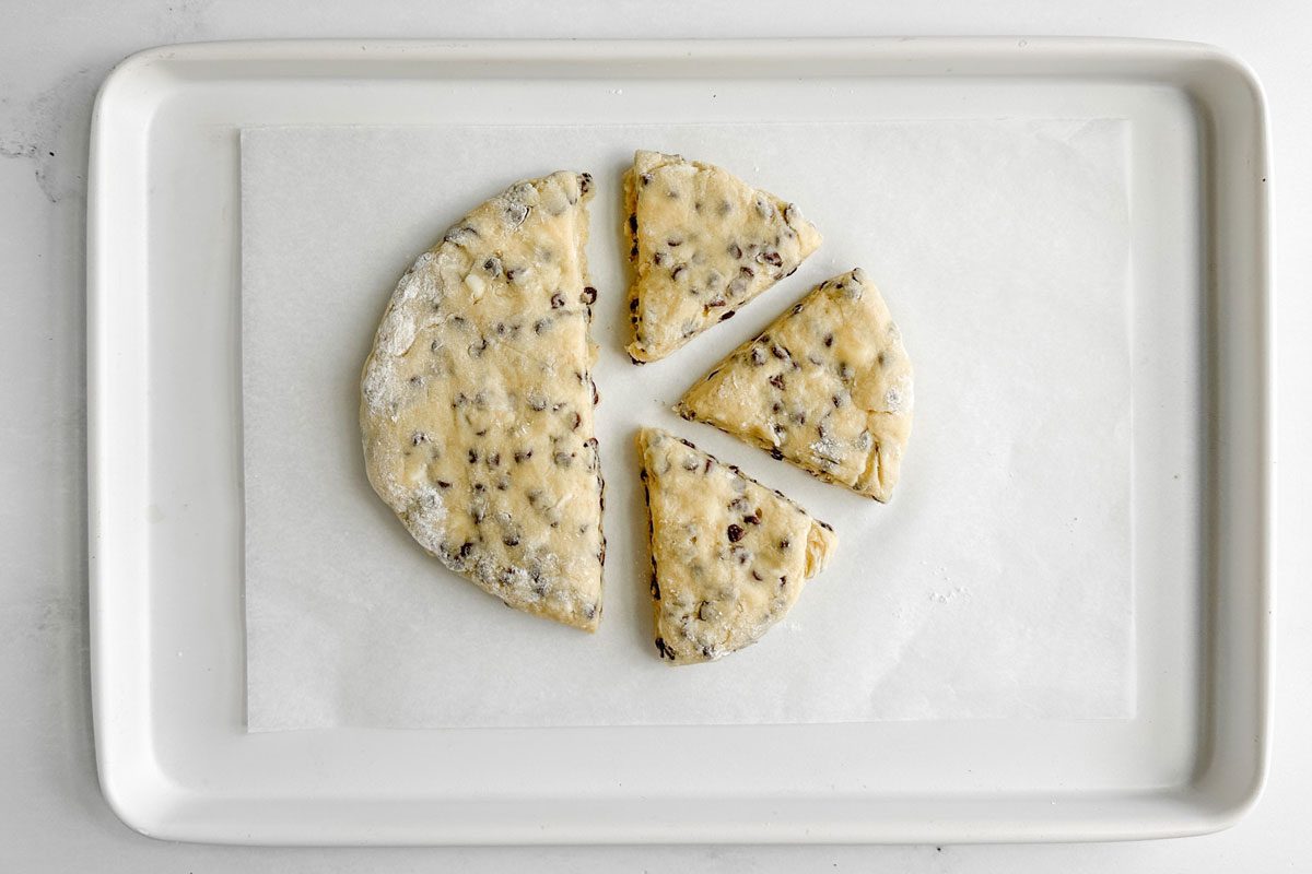 Unbaked Taste of Home Chocolate Chip Scones on a white baking sheet on a marble surface