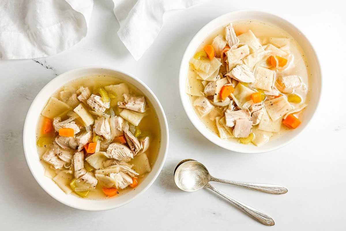 Taste of Home Copycat Cracker Barrel Chicken and Dumplings in white bowls on a marble surface
