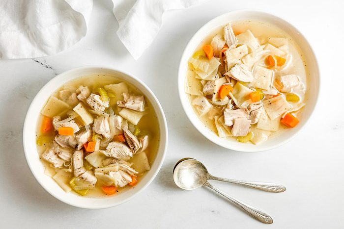 Taste of Home Copycat Cracker Barrel Chicken and Dumplings in white bowls on a marble surface