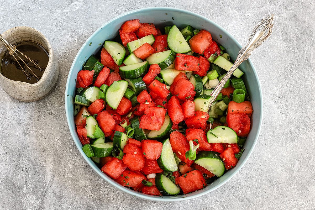 Balsamic dressing preparation for the cucumber watermelon salad, shown in a large serving bowl.