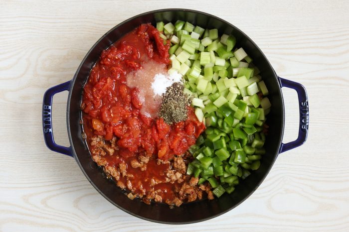 Adding vegetables and seasoning to soup