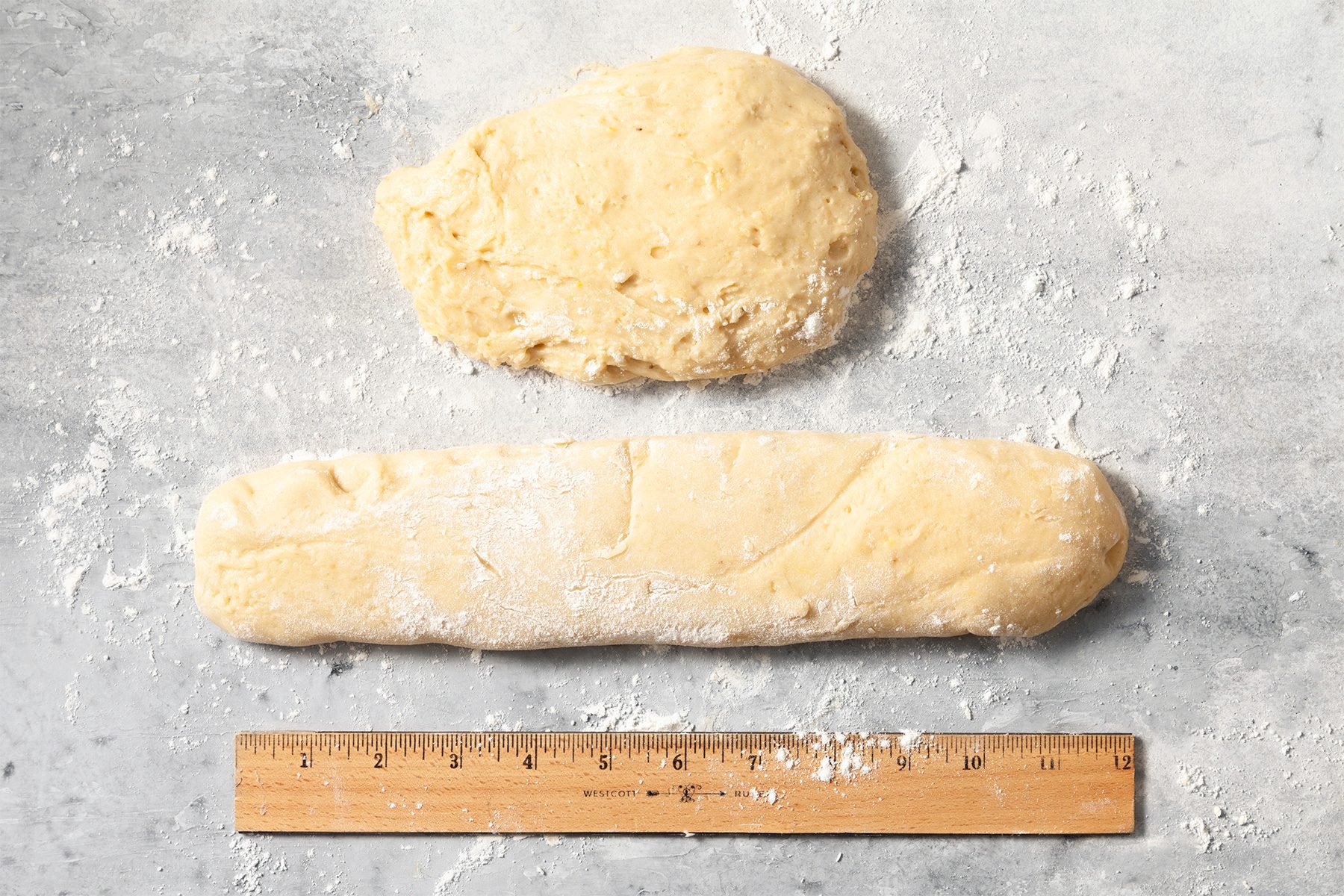 Overhead shot of divide dough in half; on a lightly floured surface shape each portion into a rectangle; wooden scale; grey marble surface;
