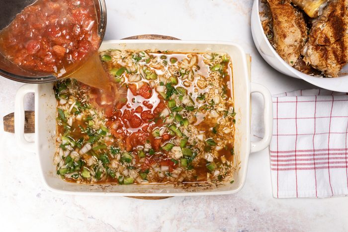 Pouring the stock and tomatoes on the rice mix