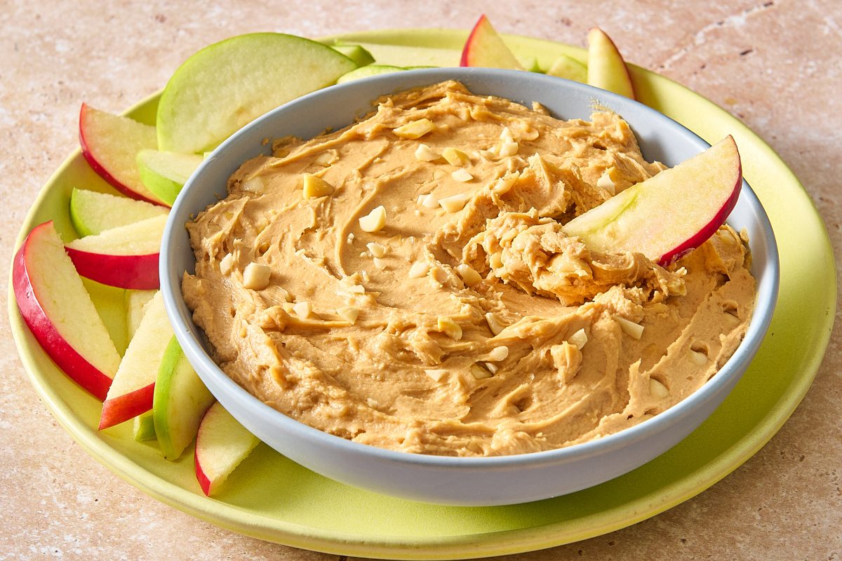 Closeup shot of peanut butter dip being scooped with an apple slice