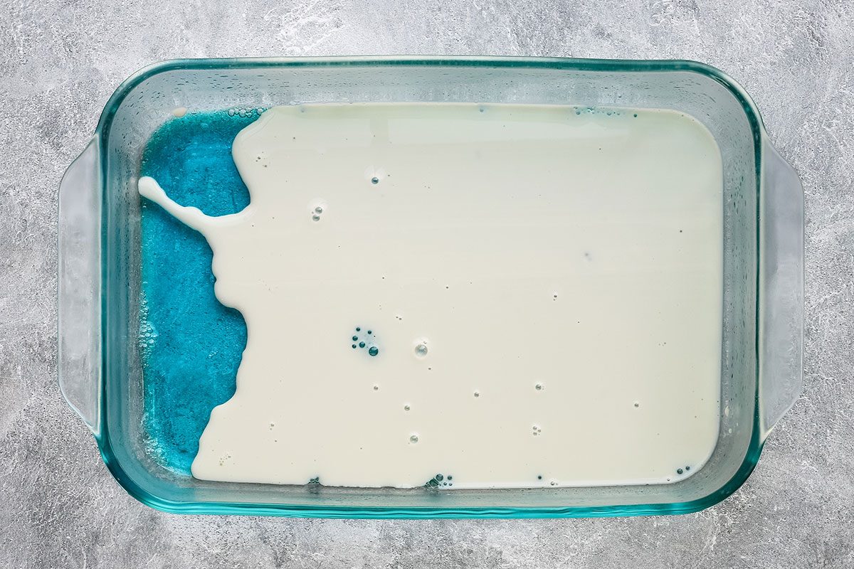 Adding the layer of sweetened condensed milk over the first layer of jello.