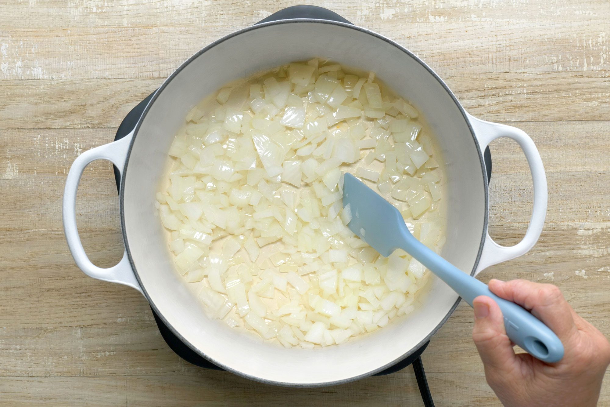 overhead shot of onion saute in a dutch oven; Wooden Background;