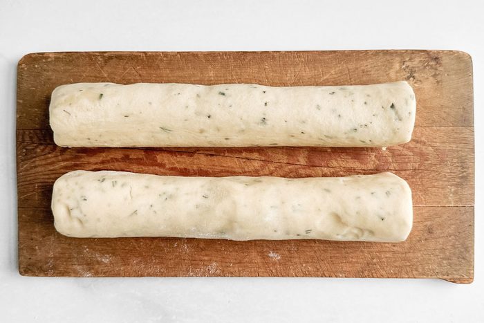 Unbaked logs for Taste of Home Rosemary Shortbread Cookies on a wooden board