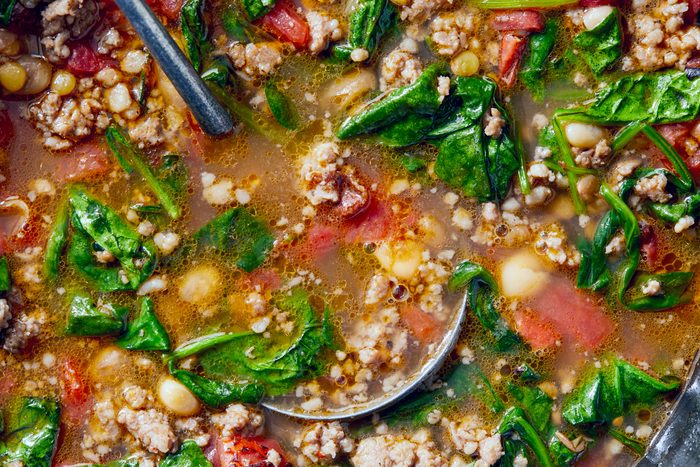 close view of Spinach and Sausage Lentil Soup, a serving spoon rests in the soup