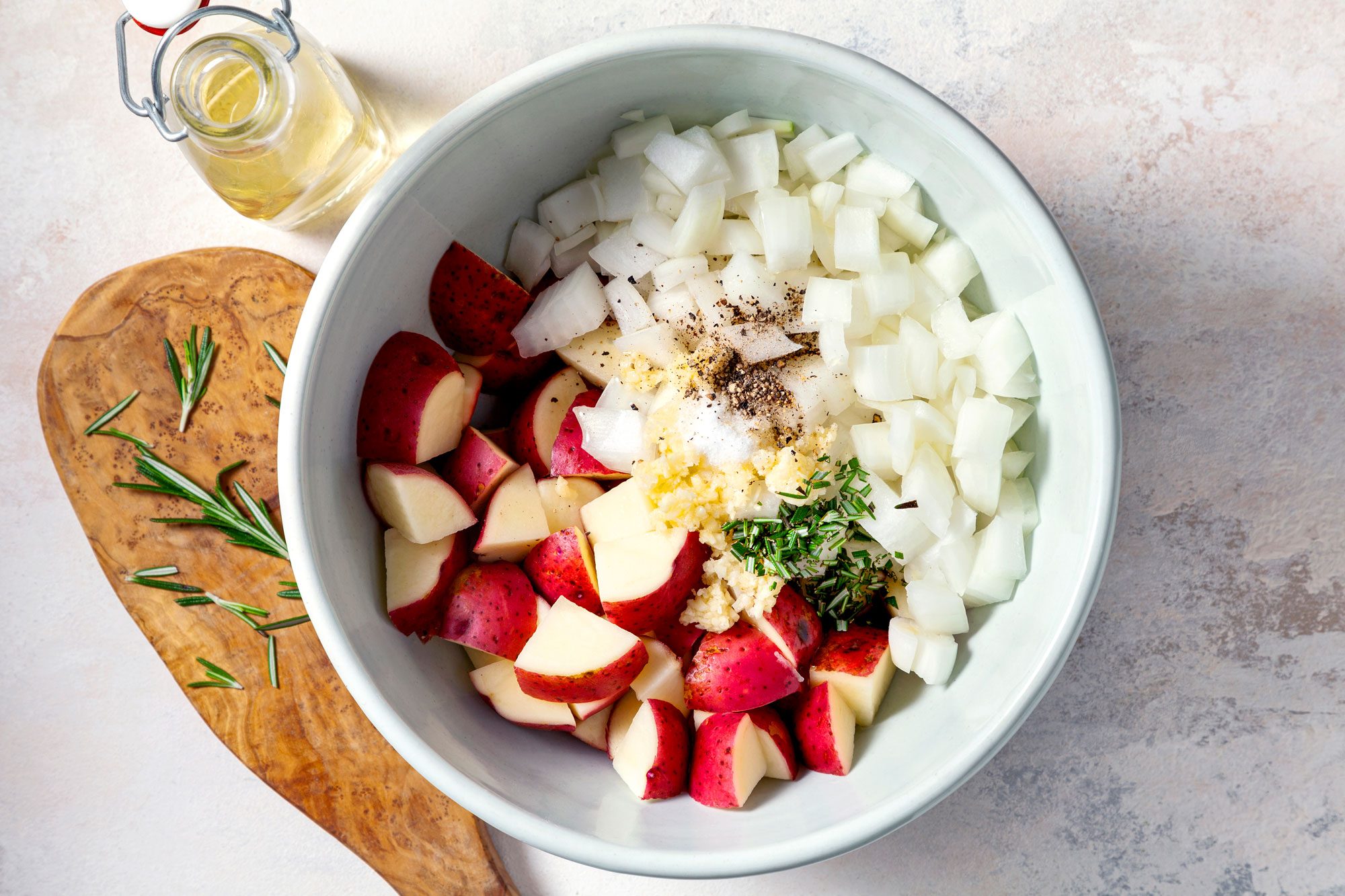 In a large bowl, combine potatoes, onion, oil, garlic, fresh or dried rosemary and toss to coat