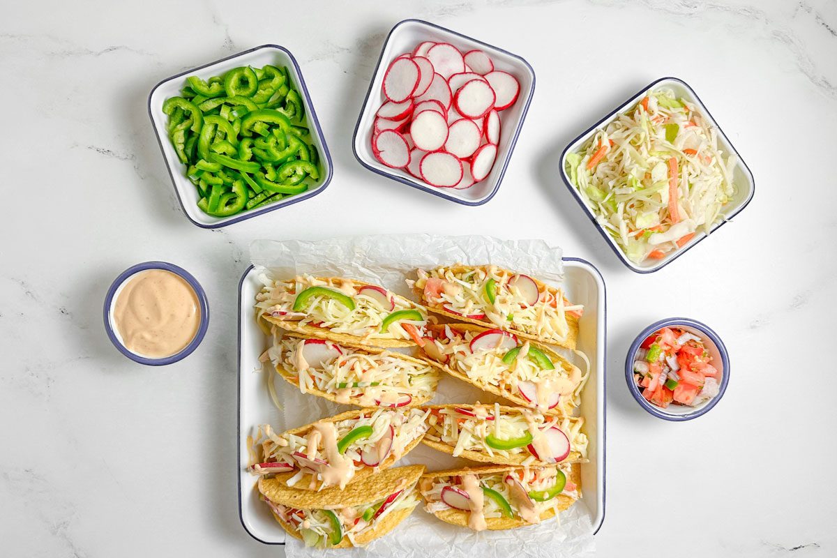 Taste of Home Shredded Chicken Tacos with assorted toppings on enamel dishes