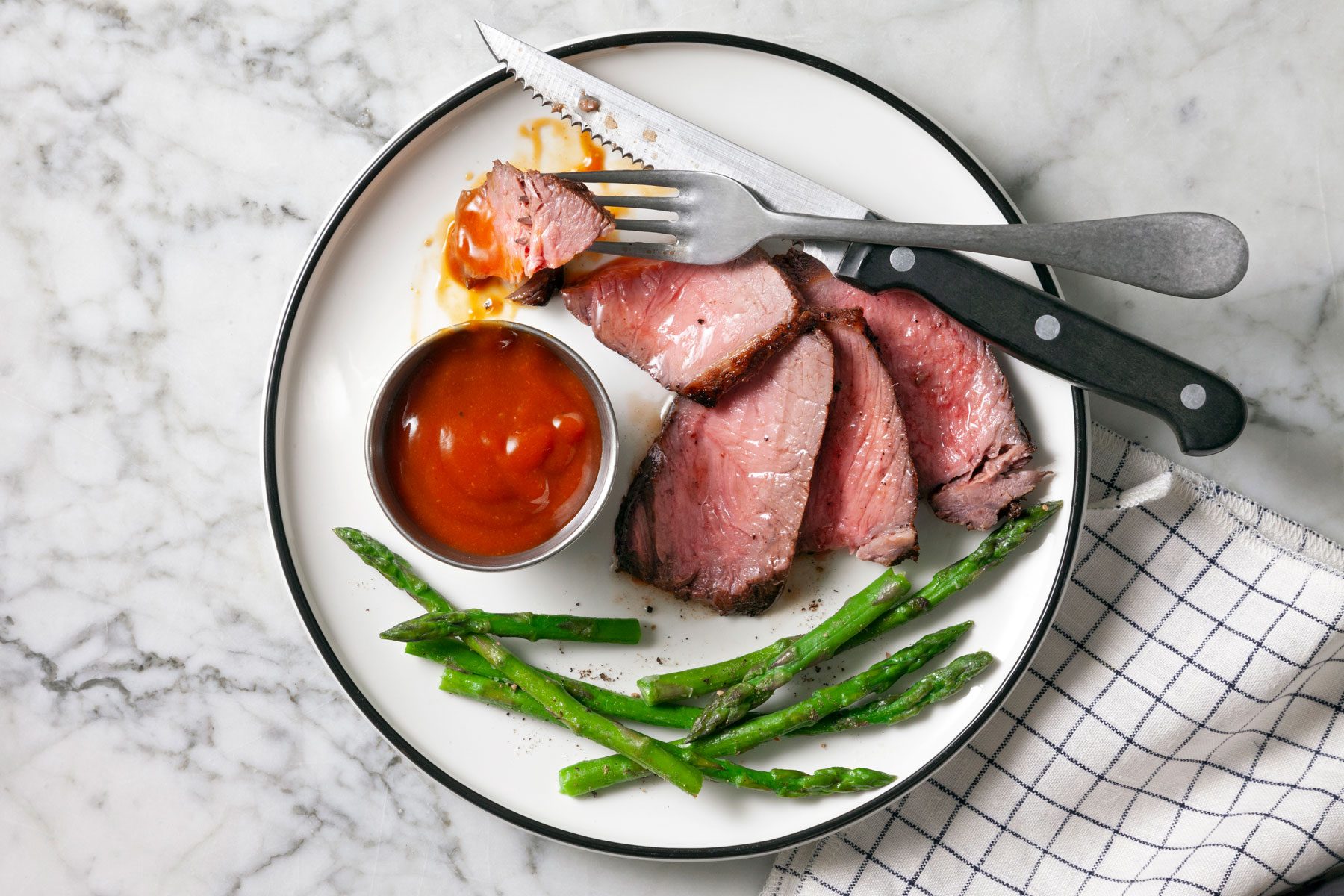 Plate containing Steak Sauce, steak slices and vegetables.
