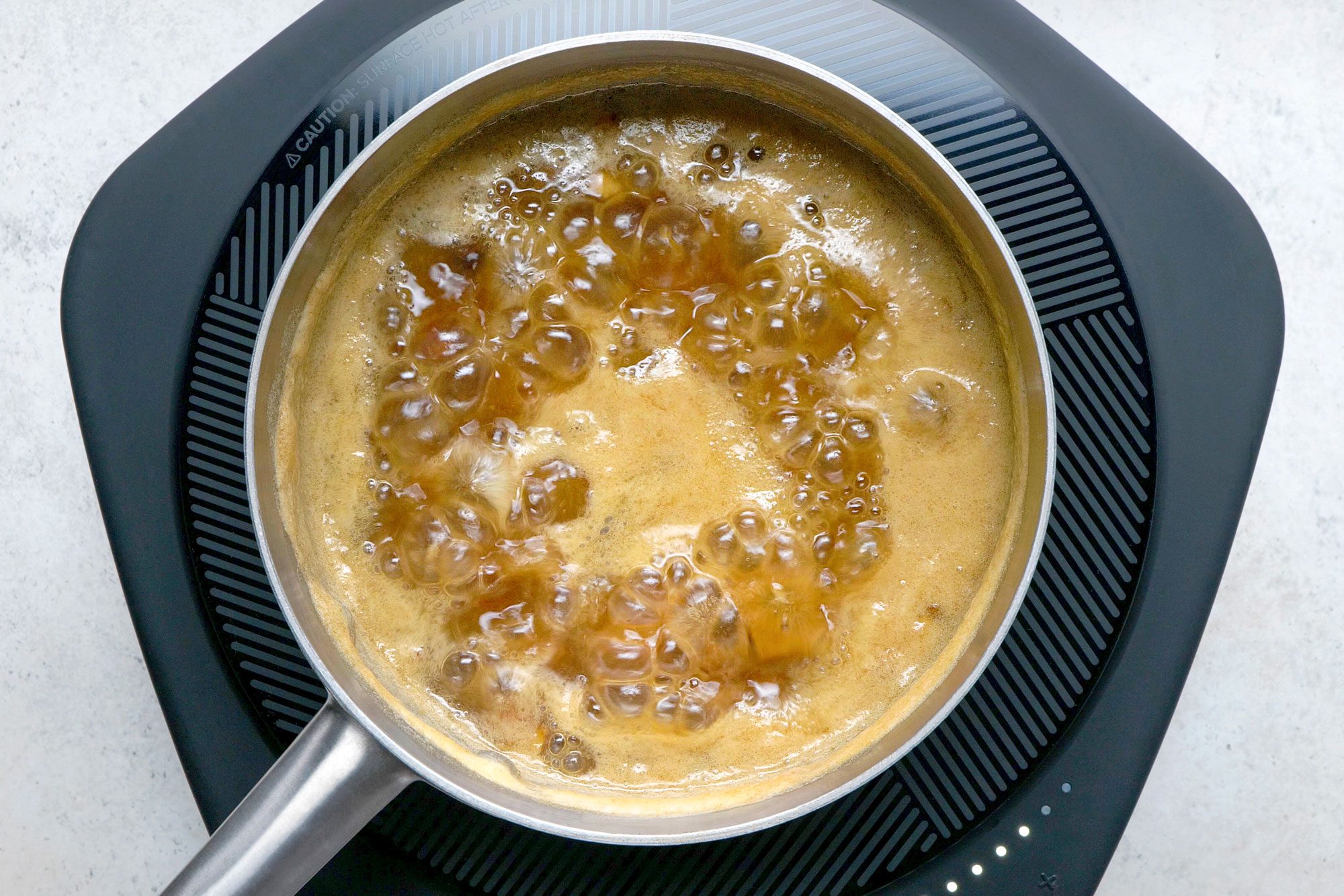 Overhead shot of a small saucepan; combine dates and water; bring to a boil; induction; marble surface;