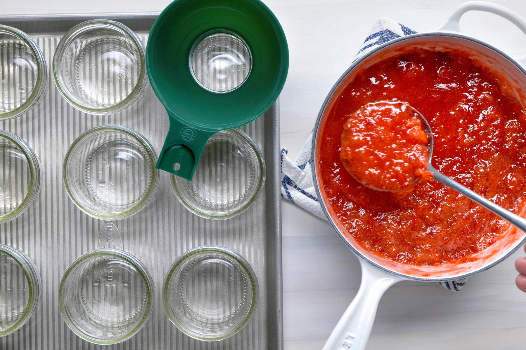 Overhead shot of ladle hot mixture into hot half-pint jars; leaving 1/4 inches headspace; remove air bubbles and adjust headspace by adding hot mixture; Wipe rims; Center lids on jars; screw on bands until fingertip tight