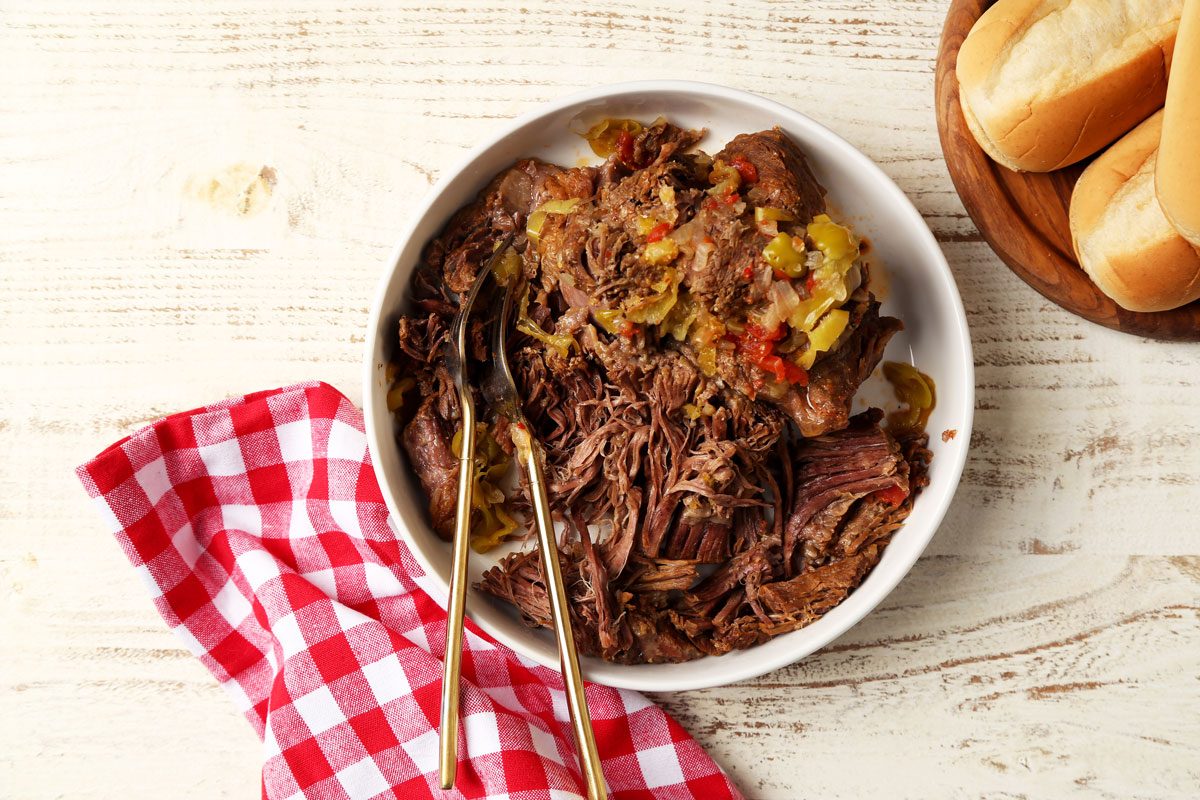 Close up of shredded Italian beef in a white bowl for Taste of Home's Italian Beef Sandwiches.