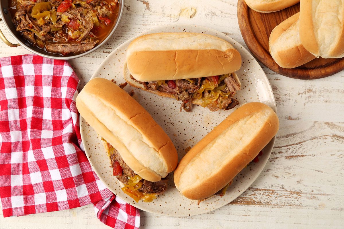 Close up of Taste of Home's Italian Beef Sandwiches served on a platter on a white wooden surface.