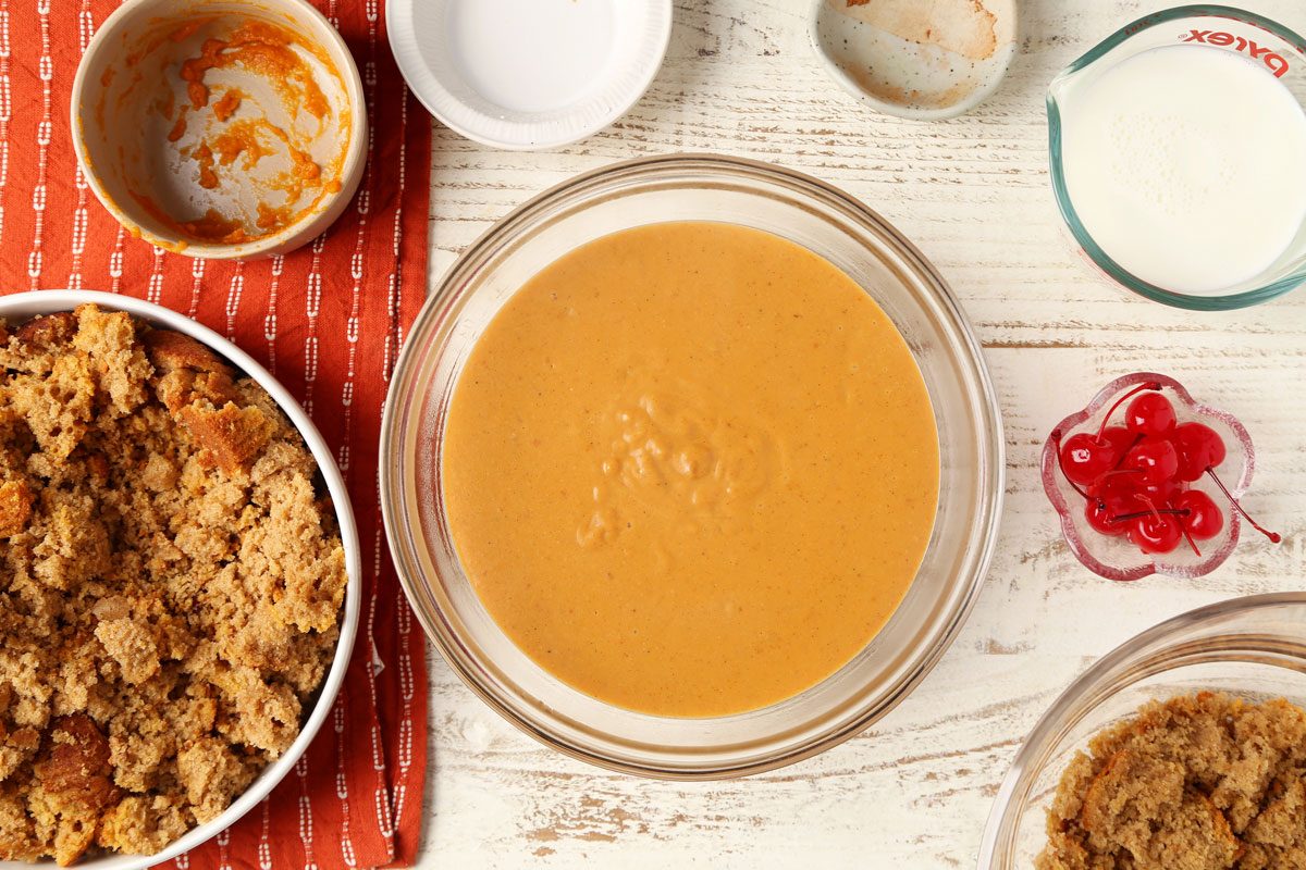 Process of making Taste of Home's Pumpkin Trifle layered in a glass serving bowl on a white wooden surface.