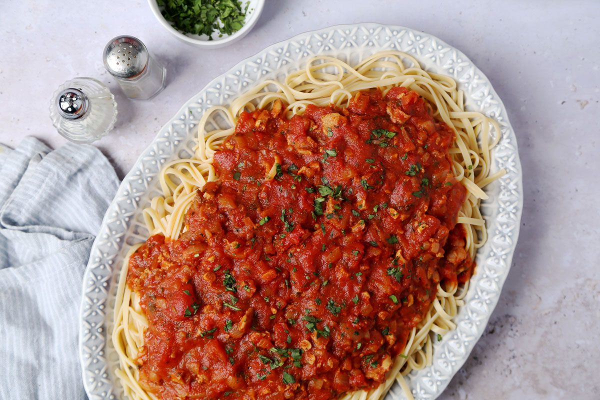 Close up of Taste of Home's Red Clam Sauce served on top of cooked linguine on a blue platter.
