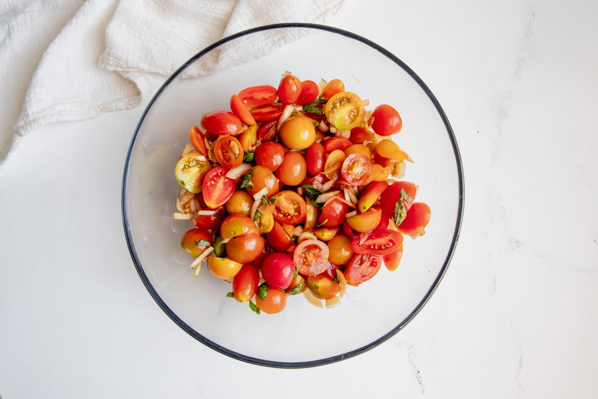 Overhead shot for Taste of Home Tomato Feta Salad with ingredients tossed in a glass bowl.