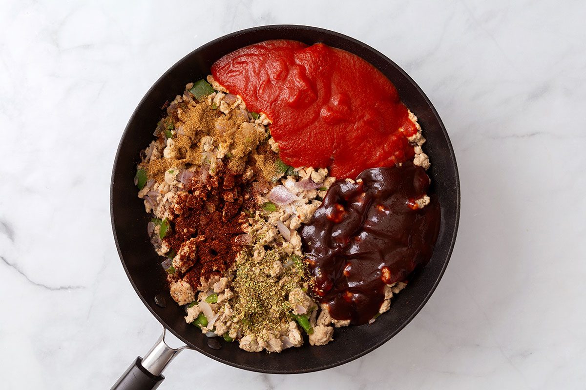 Tomato sauce, barbecue sauce, oregano, cumin, chili powder and salt mixed with cooked ground turkey, onion and green pepper in a large skillet