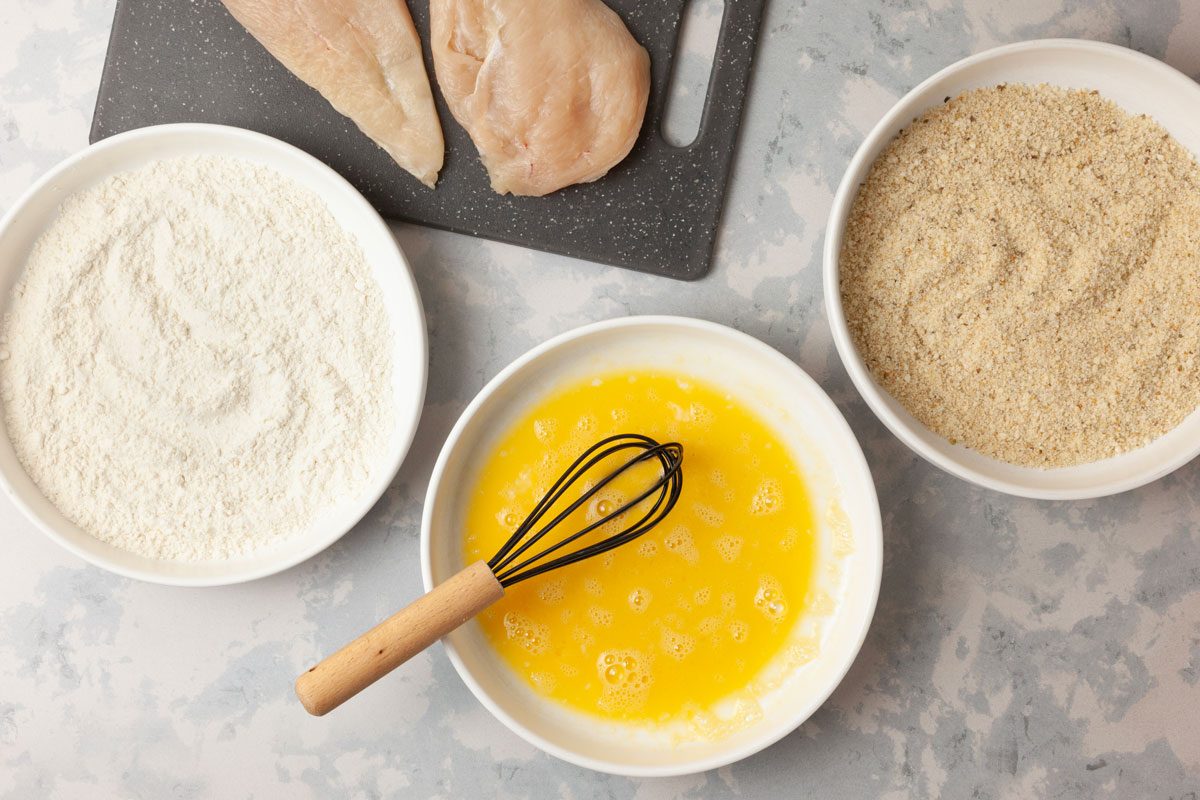 Step 1 of Taste of Home Parmesan Chicken Sandwiches is to place the flour and egg in separate shallow bowls. In another bowl, toss the bread crumbs with the Parmesan cheese.