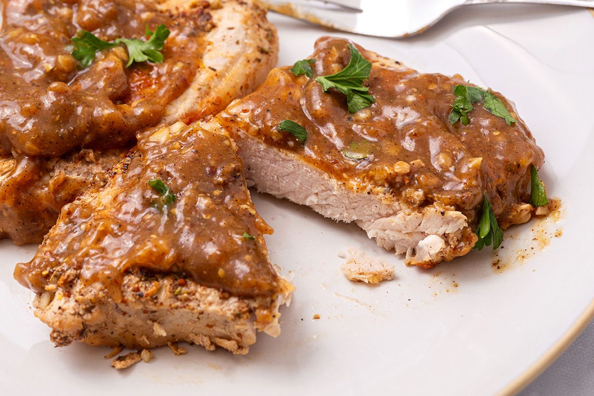 Apple Cider Pork Chops topped with parsley on a serving platter for Taste of Home