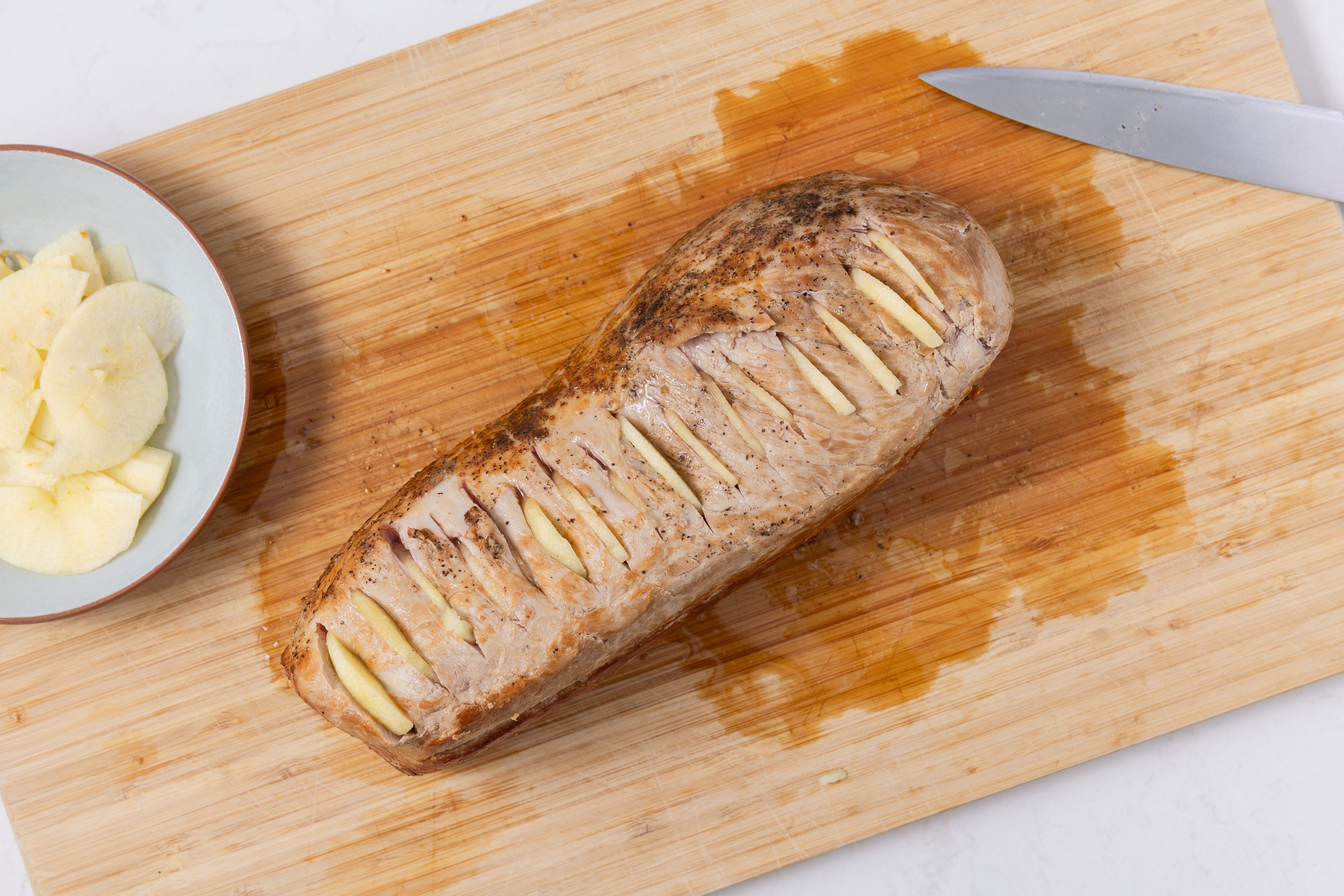 Pork loin being prepared with apple slices after being browned in skillet.