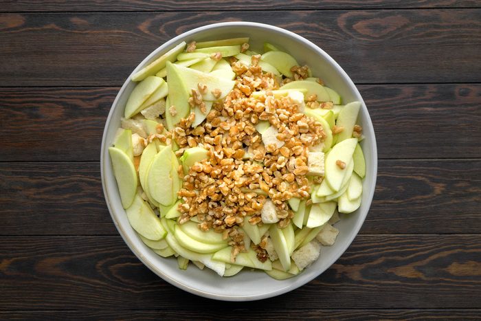 Apples, walnuts, herbs, spices, sausage and bread cubes in a bowl