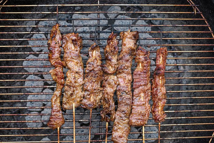 Grilling beef satay over charcoal.