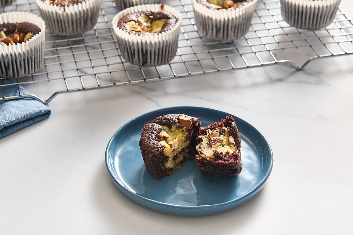 Closeup of a single black bottom cupcake on a plate split in two