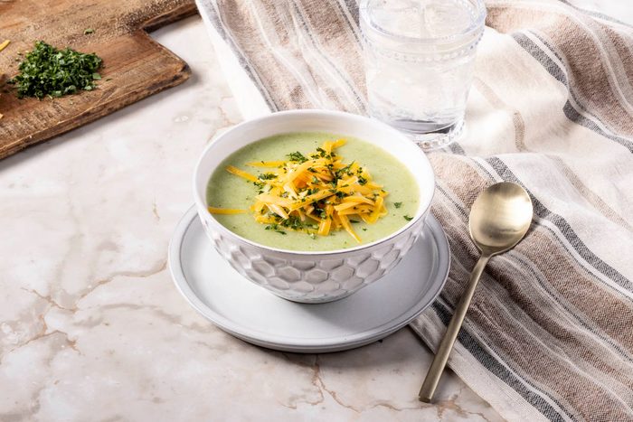 Broccoli Cheddar Potato Soup in a white bowl with a spoon on marble surface