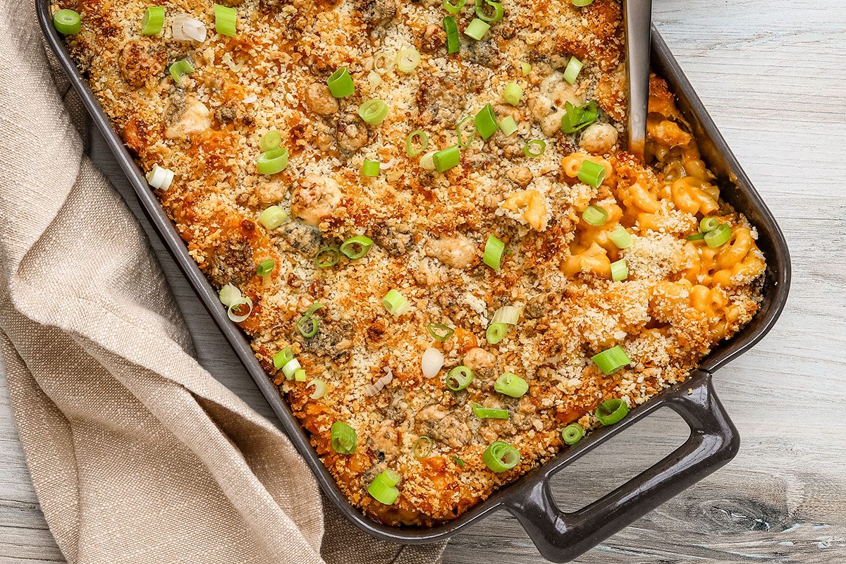 A baking dish with Buffalo mac and cheese topped with blue cheese, panko, and green onions.