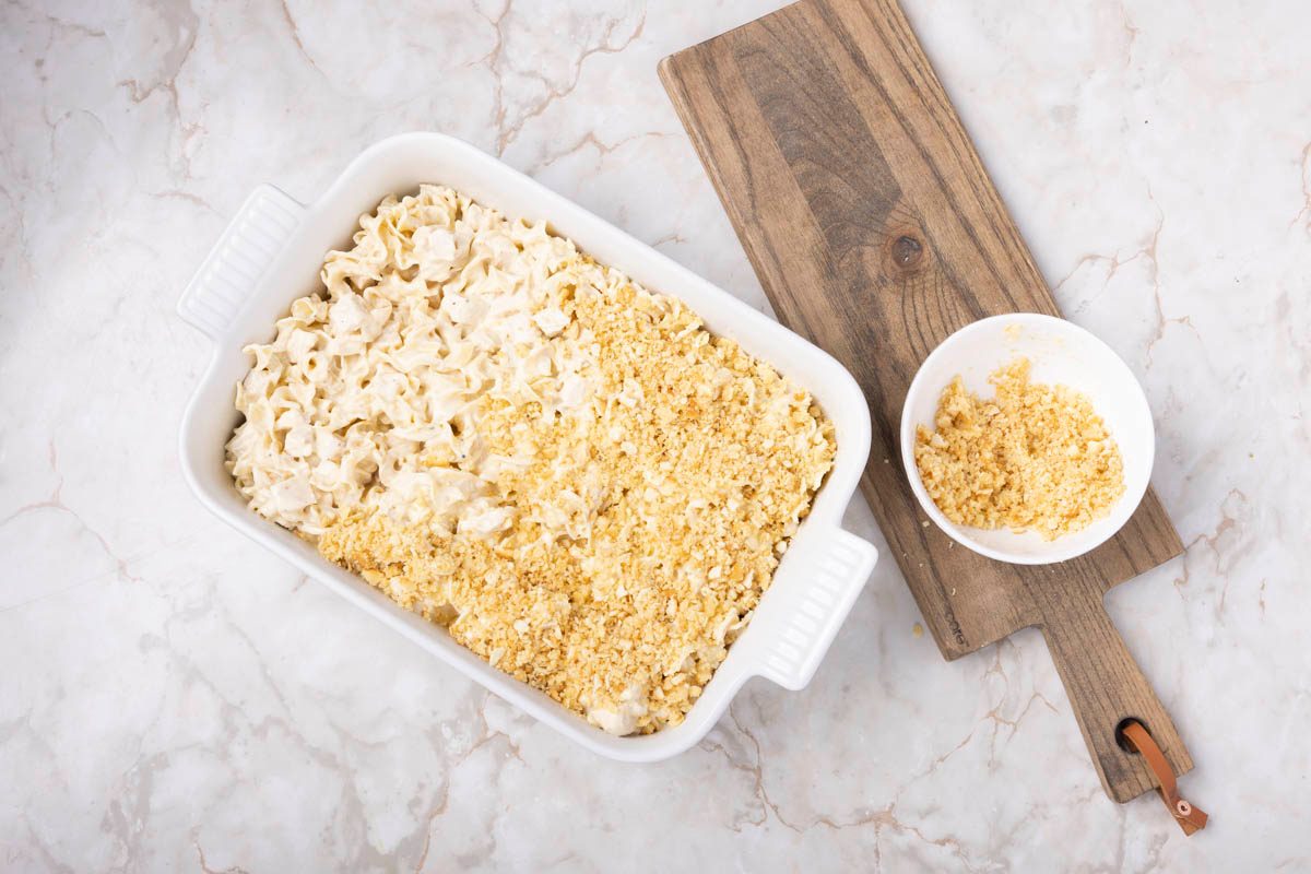 Chicken Noodle Casserole being prepared in baking dish overhead view on a marble table
