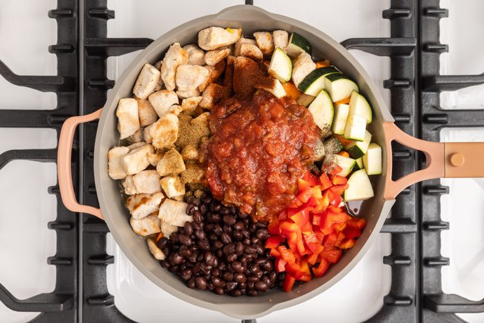 Vegetables and chicken on skillet being sauteed.