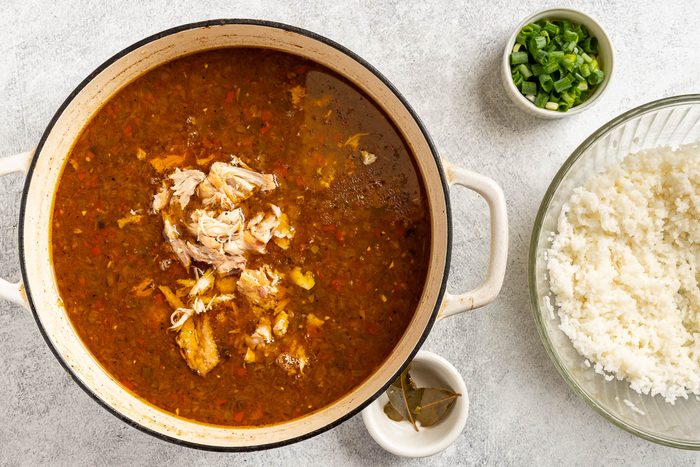 Taste of Home Chicken and Andouille Gumbo photo of the shredded chicken with optional sides of rice and green onions.