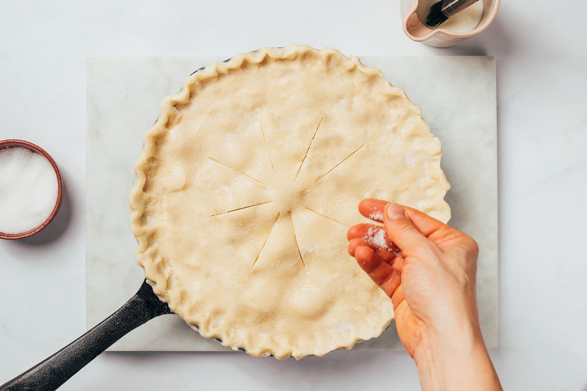 Sprinkling coarse sugar over the top of the Cinnamon Apple Pie top crust a recipe by Taste of Home