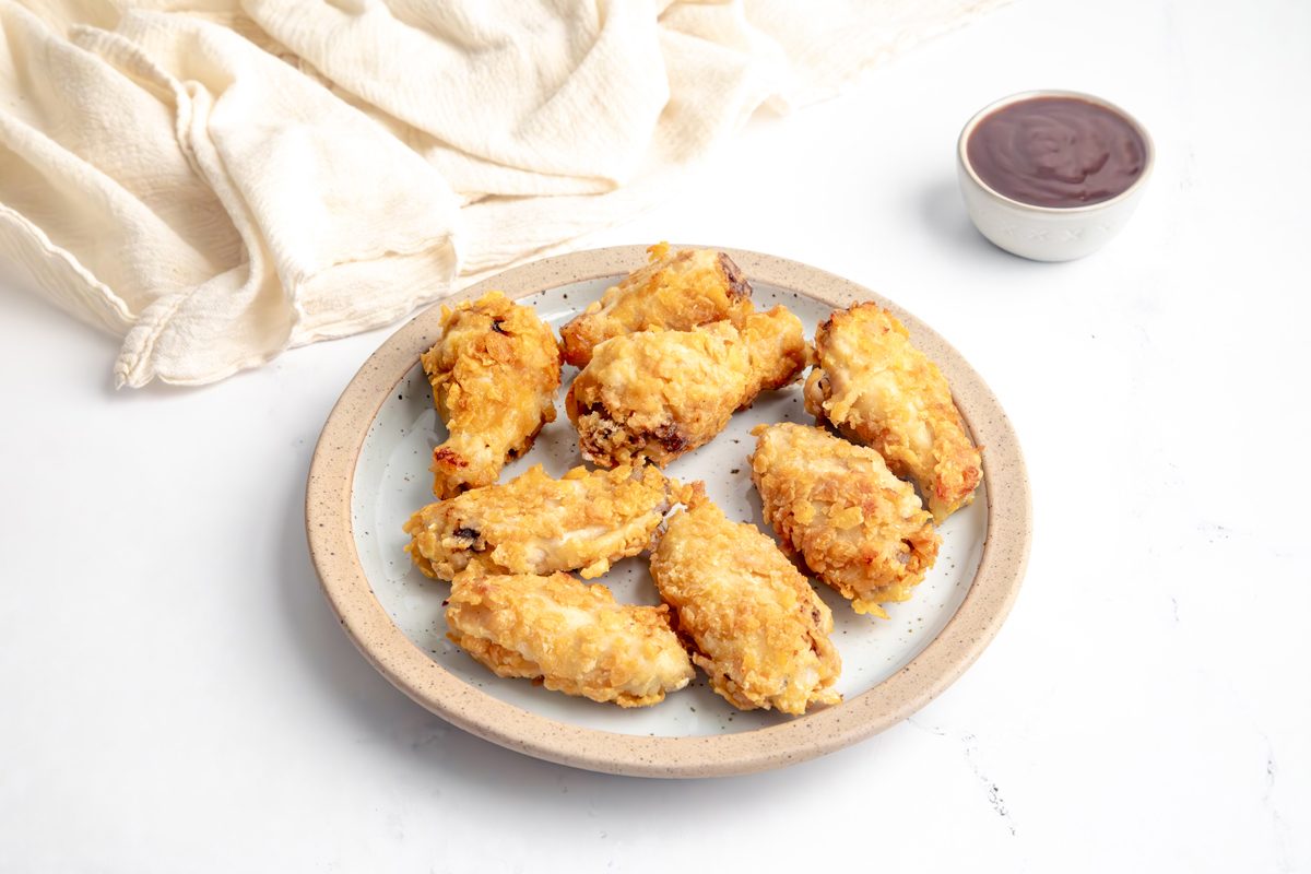Close up beauty shot for Taste of Home Cornflake Chicken with chicken being served alongside BBQ sauce on a plate.