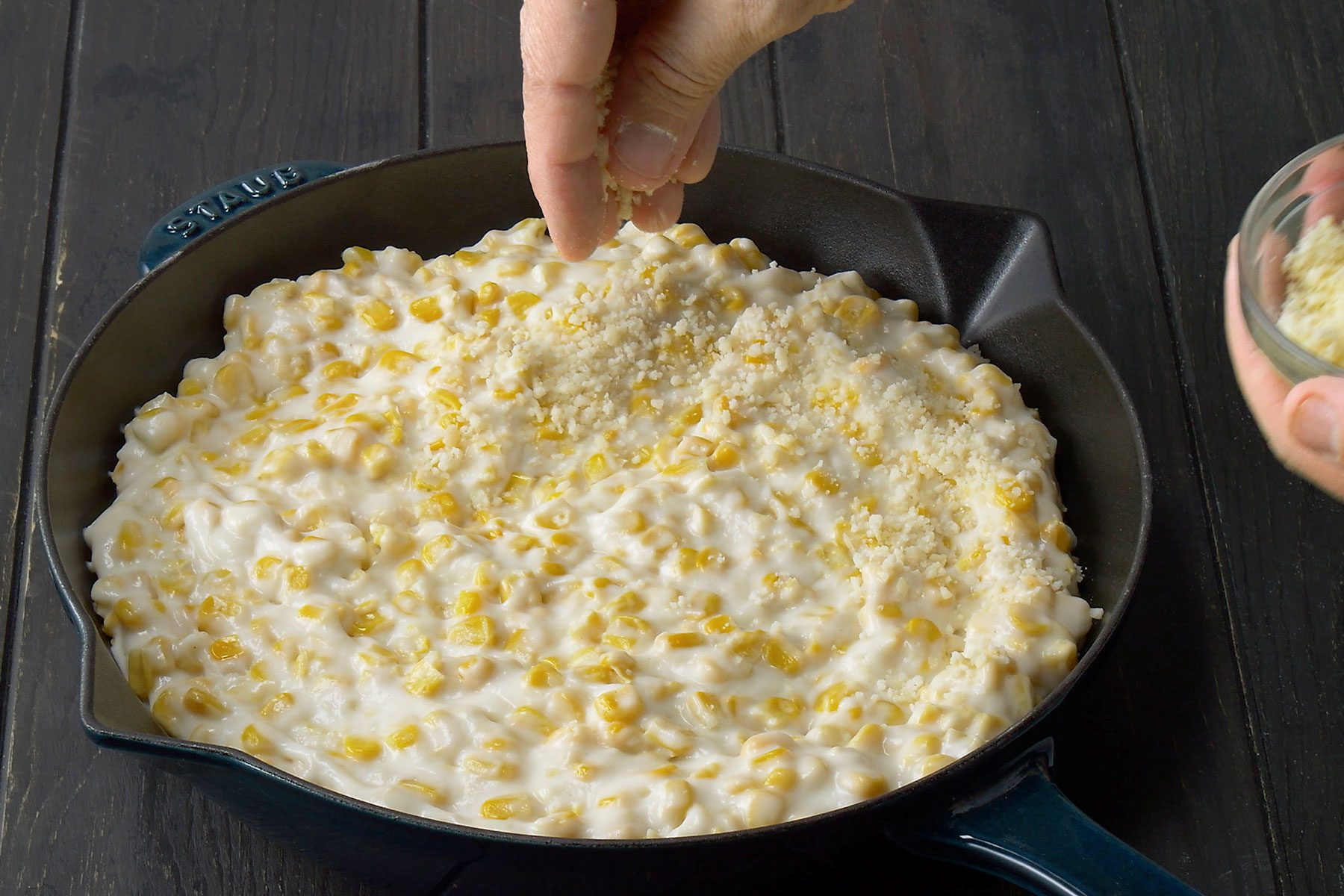 Creamed Corn being sprinkled with parmesan cheese