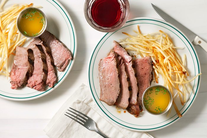 An overhead shot features a beautifully presented Florentine steak, accompanied by a generous dollop of herb garlic butter. The rich, grilled steak is garnished with fresh herbs, creating an appetizing and rustic display.