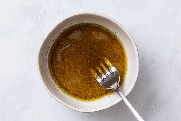 Lemon juice, olive oil and pepper mixed in a small bowl for step one of Greek Salad with Lettuce recipe for Taste of Home