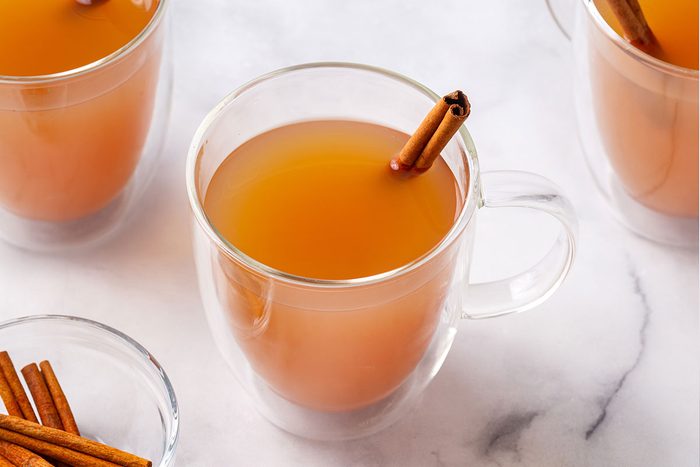 Hot Apple Cider in clear mug glasses with a cinnamon stick for Taste of Home
