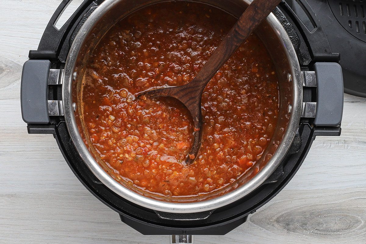 Lentil soup in the Instant Pot electric pressure cooker with a ladle.