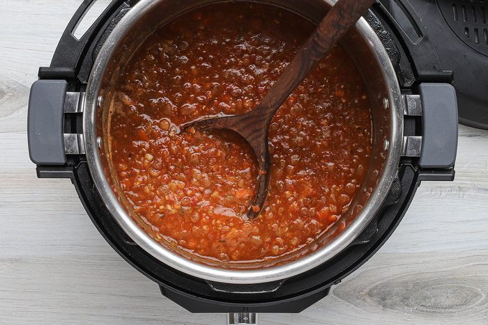 Lentil soup in the Instant Pot electric pressure cooker with a ladle.