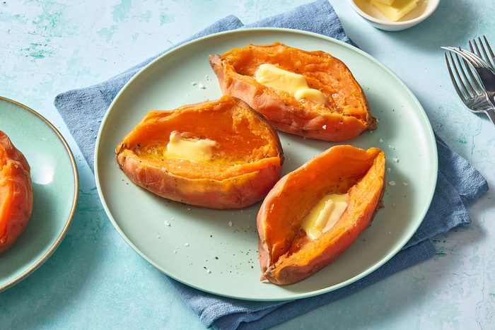 Shot of three instant pot sweet potatoes served on a plate topped with butter