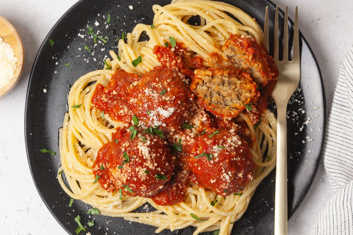 Single serving of Taste of Home Lentil Meatballs in marinara sauce, on spaghetti, garnished with parmesan and parsley