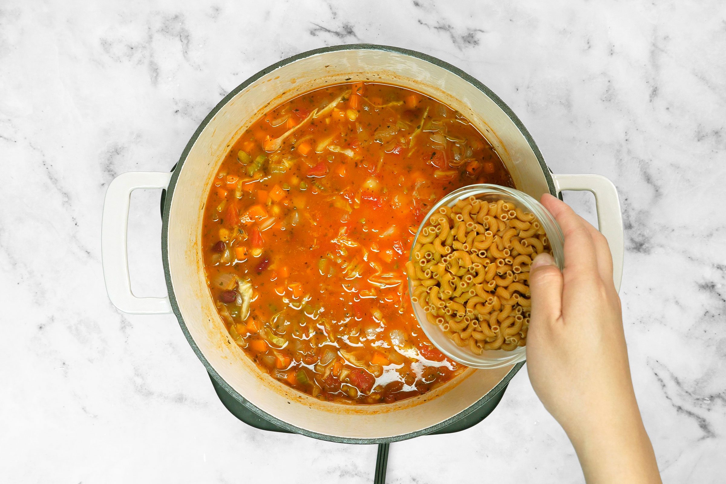 Adding elbow pasta to vegetables and broth mix