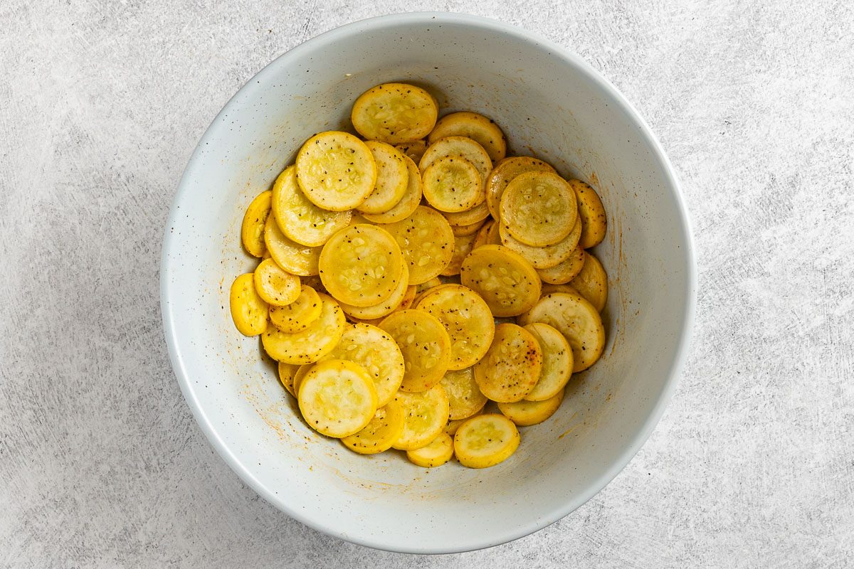 Taste of Home Oven Fried Squash photo of the sliced squash tossed with olive oil and the seasonings in a mixing bowl.