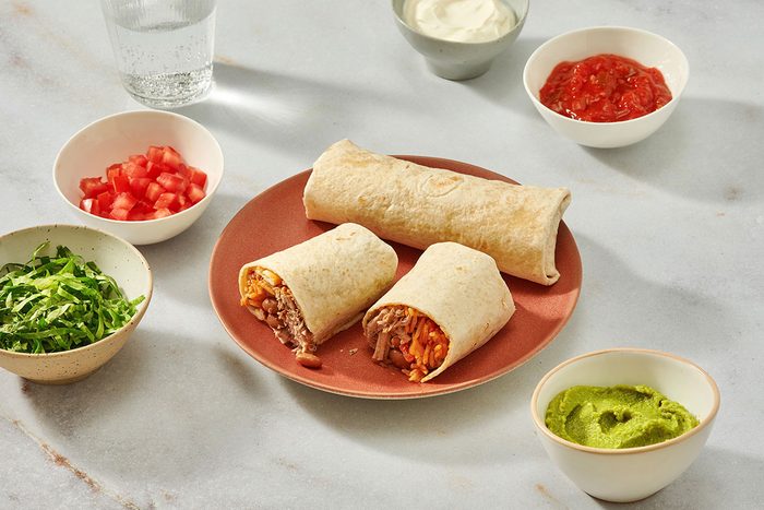 Pork burritos on a serving plate with garnishes on the side